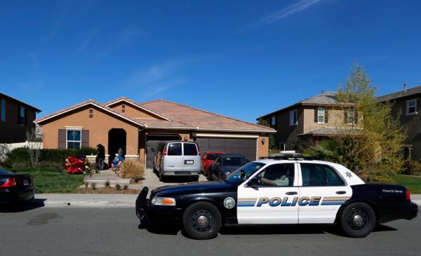 FILE - A police car drives past the home of David and Louise Turpin wher<em></em>e police arrested the couple accused of holding 13 children captive on Jan. 24, 2018, in Perris, Calif. A report released Friday, July 8, 2022, says the social services system "failed" the 13 children who were rescued after being starved, shackled to beds and horribly abused by their parents the Turpin's at their Southern California home for years. 