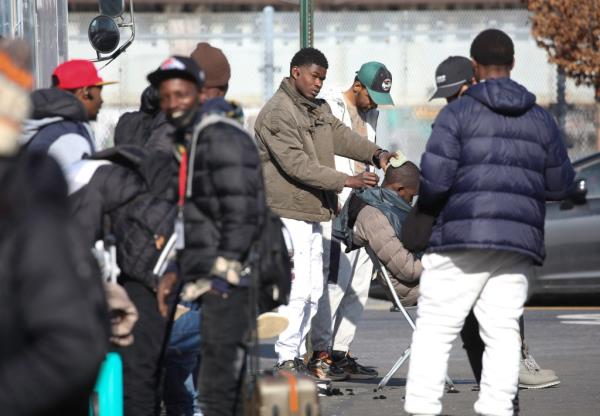 Migrants hanging out on the street outside a shelter in Long Island City. Workers there are pleased a<em></em>bout the new curfew